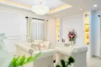 3 Bedroom House for Sale in Na Kluea sitting area with white armchairs, floral display, and lit display shelves