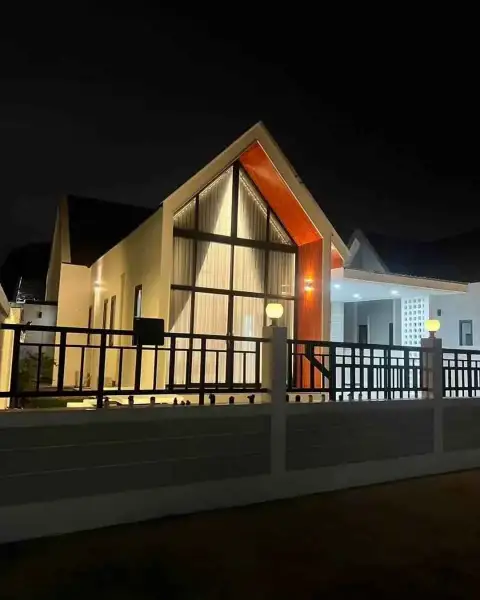 3 Bedroom House for Rent in Na Kluea exterior view with A-frame glass window and perimeter fence at night