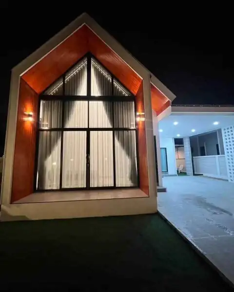 3 Bedroom House for Rent in Na Kluea close-up of peaked glass window with wood trim entrance at night