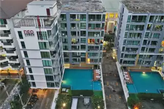 Neo Condo swimming pool with blue water, surrounded by lounge chairs and the condo building in the background.