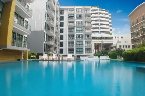 Neo Condo exterior view of the building's entrance, showing a drive-through area and surrounding greenery.