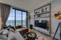 1 Bedroom Condo for Sale at Andromeda Condominium modern living area with L-shaped sofa, wall-mounted TV, and balcony sea view
