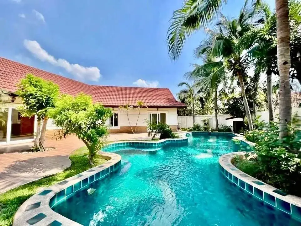 4 Bedroom House for Rent at Nirvana Pool Villa 1 freeform swimming pool surrounded by palm trees and red-roofed villa