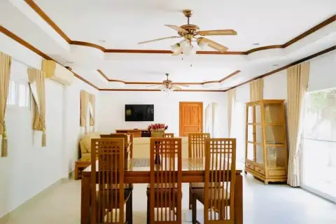 4 Bedroom House for Rent at Nirvana Pool Villa 1 wooden dining and living room with ceiling fans and TV