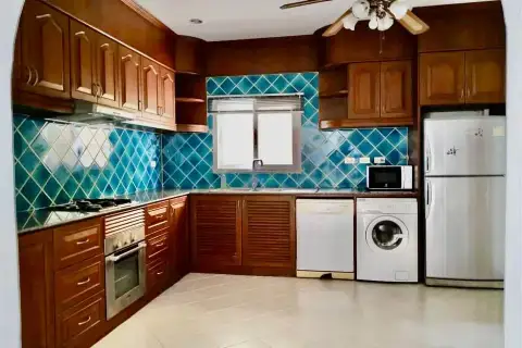 4 Bedroom House for Rent at Nirvana Pool Villa 1 kitchen with wooden cabinets, blue tile backsplash and appliances