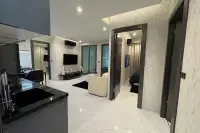 2 Bedroom Condo for Sale at Zenith Pattaya open-plan living area with marble floors, wall-mounted TV, and kitchen counter
