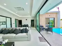 3 Bedroom House for Rent in Nong Pla Lai open-plan living room with gray sofa opening to pool terrace