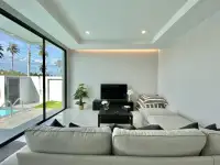 3 Bedroom House for Rent in Nong Pla Lai living room with sectional sofa and palm tree view outside