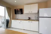 2 Bedroom Condo for Sale at Nordic Residence white kitchen with fridge, mounted TV, and balcony access
