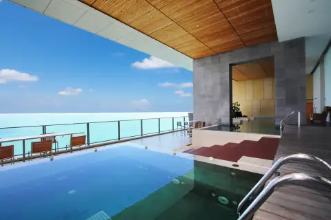 Northpoint infinity pool with ocean view, wooden deck, outdoor seating, and a covered area.