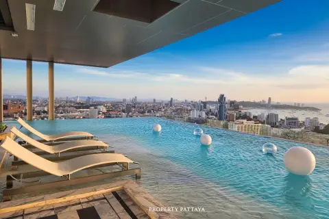 Once Pattaya rooftop infinity pool with lounge chairs overlooking the Pattaya city skyline and ocean.