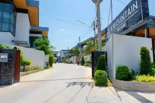M Mountain Village gated entrance with wide internal road lined with modern two-storey houses