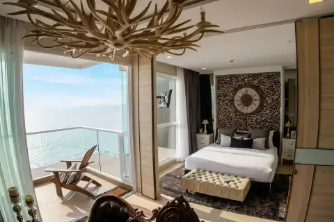 1 Bedroom Condo for Sale at Cetus Beachfront master bedroom with antler chandelier, decorative headboard wall, and ocean balcony view
