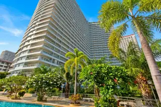 View Talay 7 tall condo building exterior surrounded by lush palm trees and gardens