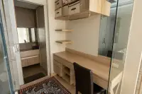 1 Bedroom Condo for Rent at Cetus Beachfront wooden study desk with shelves and storage next to glass-walled bathroom