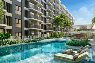 SO Origin Pattaya modern condo building exterior with a large swimming pool, submerged loungers, and lush tropical landscaping.