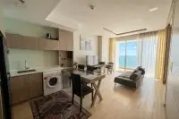 1 Bedroom Condo for Rent at Cetus Beachfront open-plan living area with kitchen, dining table, sofa, and sea view balcony