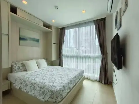 2 Bedroom Condo for Rent at Olympus City Garden bedroom with floral bedding and city view window