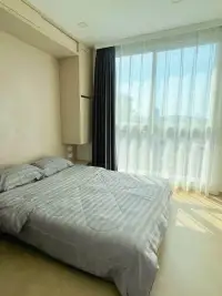 2 Bedroom Condo for Sale at Olympus City Garden bedroom with striped bedding and large window overlooking city