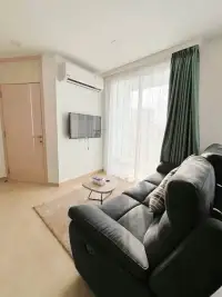 2 Bedroom Condo for Sale at Olympus City Garden living area with reclining sofa, wall-mounted TV and sheer curtains
