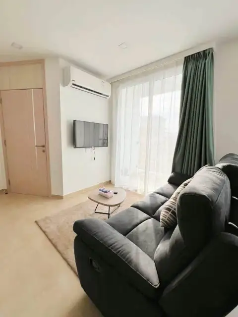 2 Bedroom Condo for Sale at Olympus City Garden living area with reclining sofa, wall-mounted TV and sheer curtains