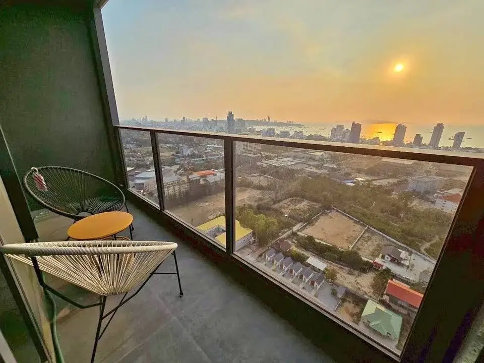 2 Bedroom Condo for Sale at Once Pattaya balcony with rattan chairs overlooking sunset city and sea view