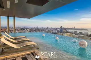Once Pattaya rooftop infinity pool with lounge chairs overlooking the Pattaya city skyline and ocean.