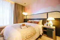 1 Bedroom Condo for Sale at Arom Jomtien bedroom with rattan headboard, pink accent wall, and pendant chandelier