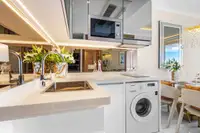 1 Bedroom Condo for Sale at The Riviera Palm Beach compact kitchen with white countertops, sink, and washing machine.