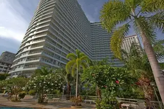 View Talay 7 exterior of the tall white condominium building surrounded by lush tropical landscaping.