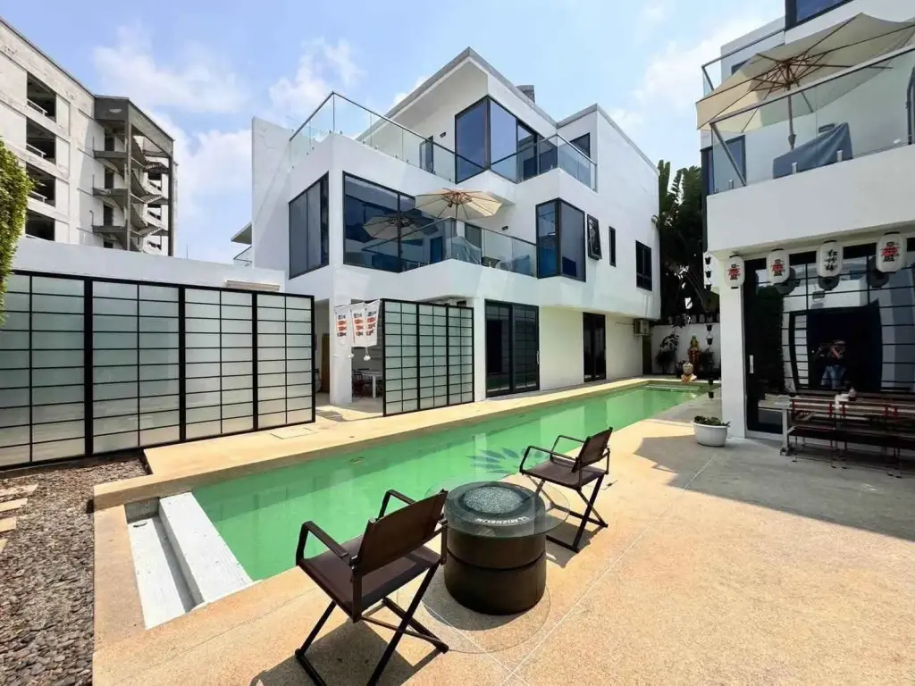 4 Bedroom House for Sale at Palm Spring villa Pattaya modern exterior with green lap pool and poolside seating area