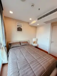 2 Bedroom Condo for Sale at Palm Wongamat second bedroom with striped bedding and bedside lamp