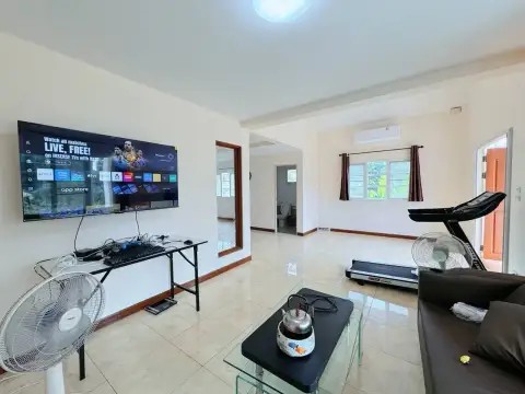 4 Bedroom House for Rent at Park Hill Village living room with wall-mounted TV, treadmill and leather sofa