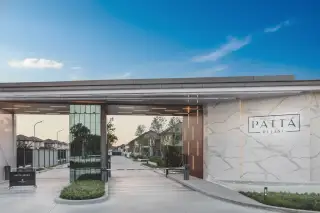 Patta Define entrance gate with security barriers, a marble-patterned wall, and residential buildings in the background.