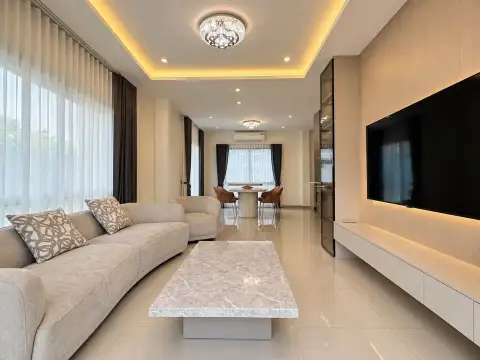 4 Bedroom House for Rent at Patta Element cozy lounge with sectional sofa, ottoman, and wood-paneled TV wall