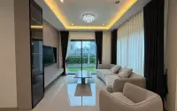 4 Bedroom House for Rent at Patta Element living room with curved sofa, wall-mounted TV and sliding glass doors