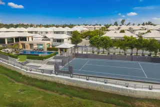 Patta Prime aerial view of the community with houses, a tennis court, and a large swimming pool.