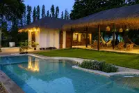 4 Bedroom House for Rent in Huai Yai thatched-roof house with curved pool illuminated at twilight