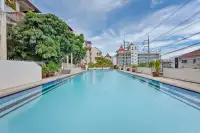8 Bedroom House for Sale in Pratumnak Hill large outdoor lap pool with tropical trees and Pattaya city buildings in background