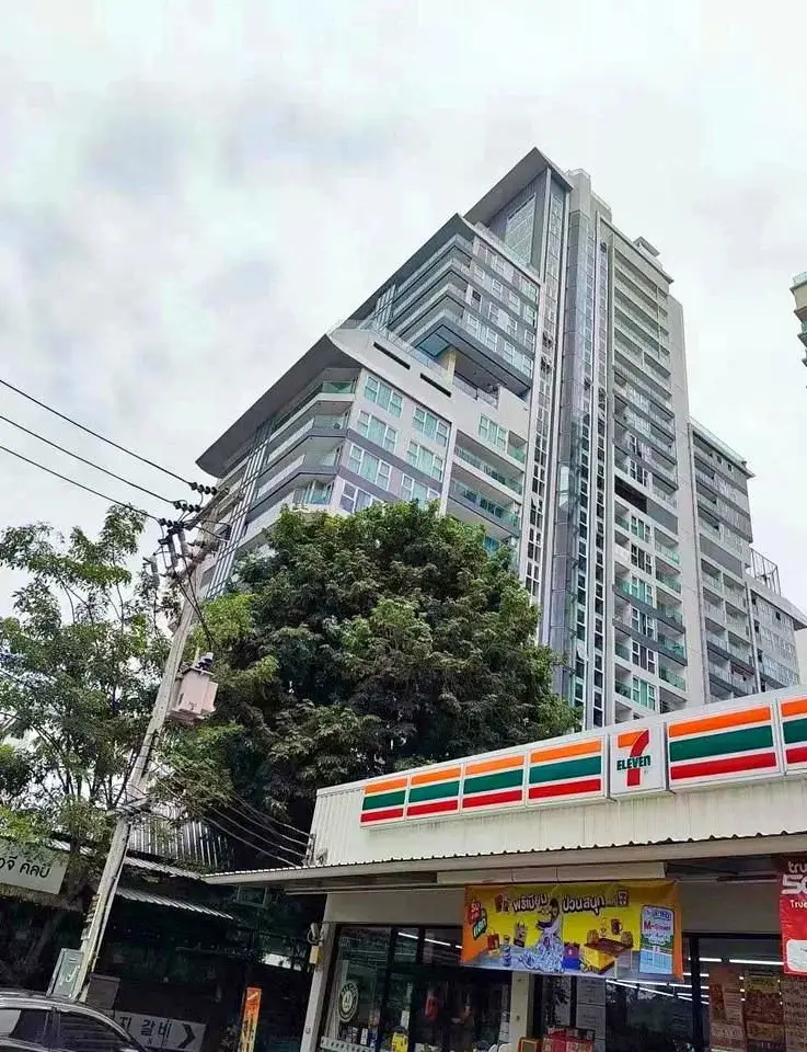 Studio Condo for Sale at Cosy Beach View high-rise exterior street view with 7-Eleven storefront in Pattaya