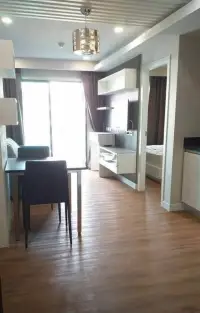 1 Bedroom Condo for Sale in Jomtien open-plan living area with dining table and wood flooring leading to bedroom
