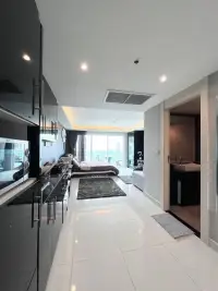 Studio Condo for Sale at Cosy Beach View open studio layout with bed, black kitchen cabinets, and city view