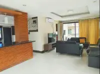 3 Bedroom House for Rent in Central Pattaya open-plan living room with black leather sofas and wooden bar partition