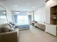 Studio Condo for Sale at Wongamat Garden Beach Resort living space with sofa, bed, and built-in storage shelves