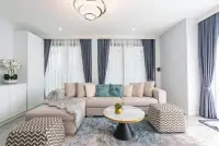5 Bedroom House for Sale bright living room with beige sectional sofa and patterned ottomans