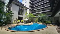 1 Bedroom Condo for Sale outdoor swimming pool surrounded by tropical landscaping and condo tower