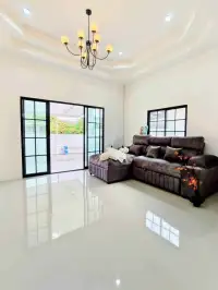 3 Bedroom House for Sale in Pattaya - living room with gray sectional sofa, chandelier, and patio doors