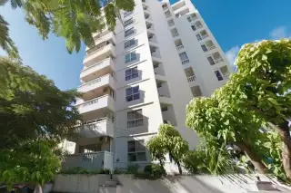 Pattaya Tower condo building exterior with multiple balconies and surrounding green trees under a clear blue sky.