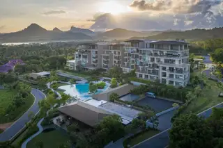 Sunplay Bangsaray: Aerial view of condo buildings, large swimming pool, lush landscaping, and mountains at sunset.
