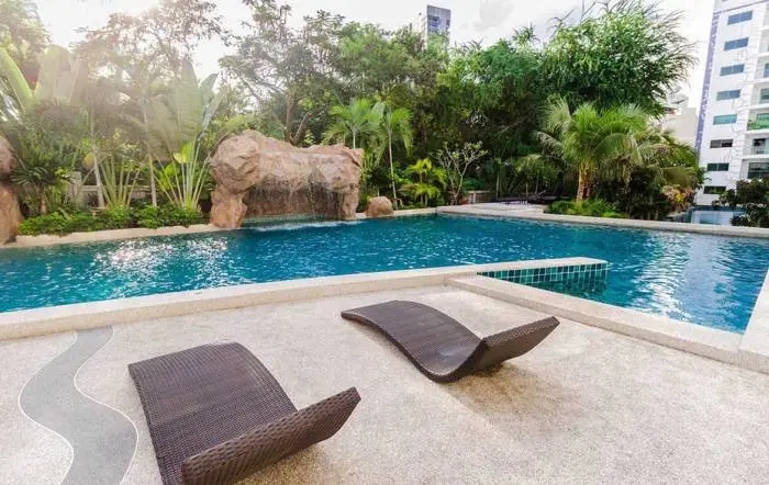 Club Royal outdoor swimming pool with rock waterfall, tropical landscaping, and two lounge chairs on the patio.
